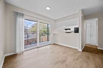 A spacious room with a sliding glass door leading to a balcony.